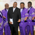 A group of men in purple suits posing for the camera.