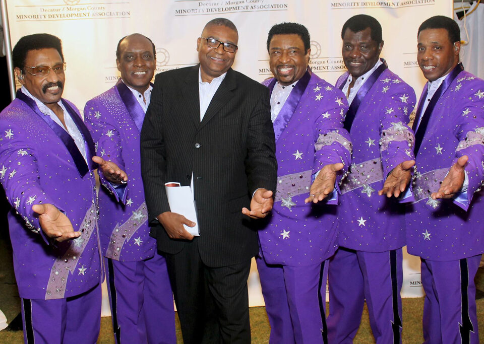 A group of men in purple suits posing for the camera.