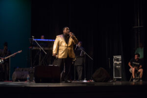 A man in a yellow jacket singing on stage